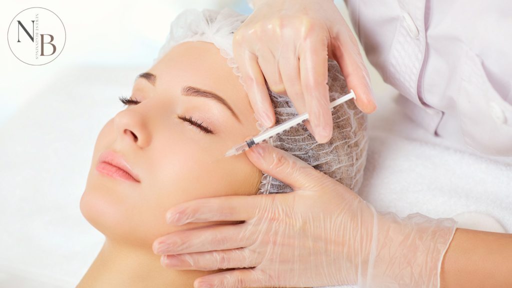 A woman receiving a Botox injection near her temple while lying down, performed by a professional wearing medical gloves.