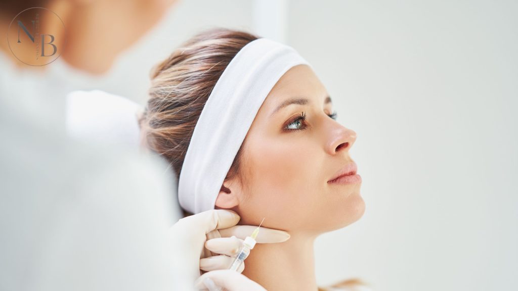 A woman receiving a Botox injection in the jawline area for facial contouring, administered by a professional