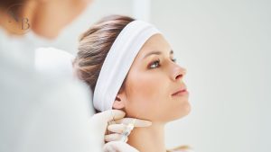 A woman receiving a Botox injection in the jawline area for facial contouring, administered by a professional